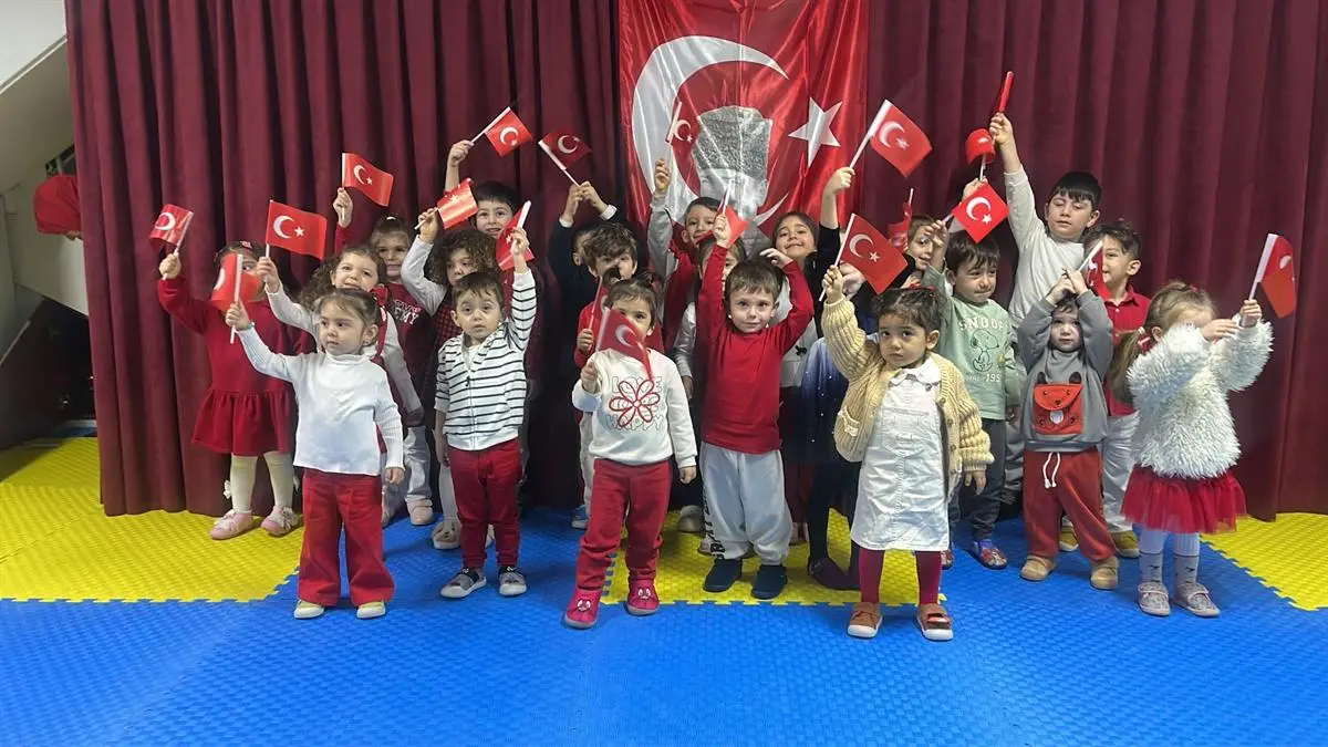 Türk bayrağının önünde ellerinde bayraklarla duran çocuklar